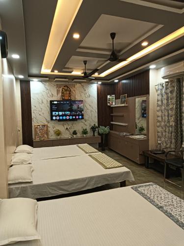 a bedroom with three beds and a tv on the wall at Shri SeetaRam Home Stay Near Shri Ram Janmabhoomi Mandir Ayodhya in Ayodhya