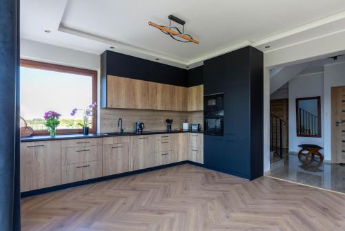 a kitchen with wooden cabinets and a large window at Ogrodowy Zakątek in Łebcz
