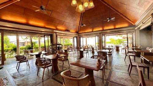 a restaurant with wooden tables and chairs and windows at Deva Beach Resort Samui in Choeng Mon Beach