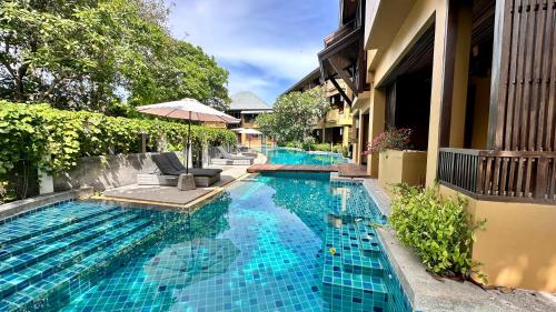 a swimming pool with a chair and an umbrella at Deva Beach Resort Samui in Choeng Mon Beach
