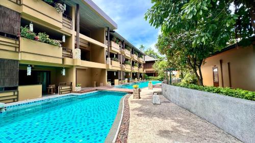 a swimming pool in front of a building at Deva Beach Resort Samui in Choeng Mon Beach