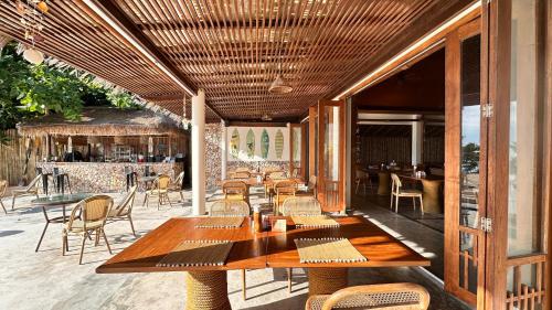 a restaurant with wooden tables and chairs on a patio at Deva Beach Resort Samui in Choeng Mon Beach