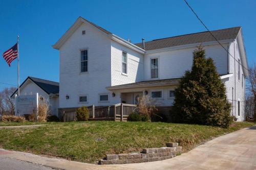 a white house with an american flag in front of it at Historic Simmons Estate sleeps 20 in Williamstown