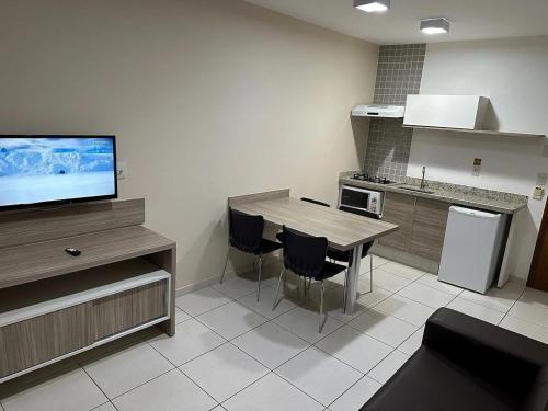 a kitchen with a table and chairs and a television at Apartamentos Riviera Park in Caldas Novas