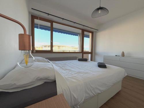 une chambre avec un lit blanc et une fenêtre dans l'établissement M2 Marquer Appartement spacieux et lumineux avec balcon à deux pas du centre ville, à Annemasse