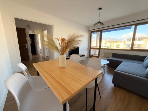 un salon avec une table en bois et des chaises blanches dans l'établissement M2 Marquer Appartement spacieux et lumineux avec balcon à deux pas du centre ville, à Annemasse