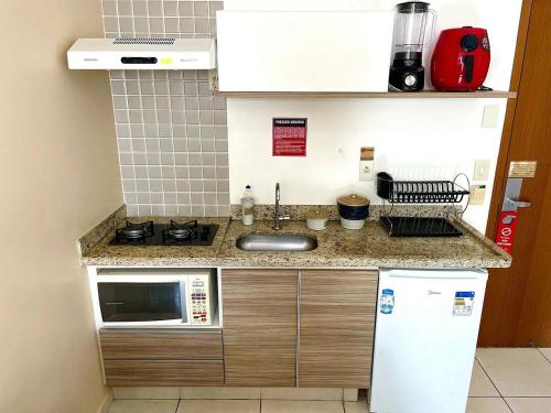 a small kitchen with a sink and a microwave at Apartamentos Riviera Park in Caldas Novas