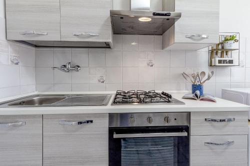 a white kitchen with a stove and a sink at S'ammentu in Sassari