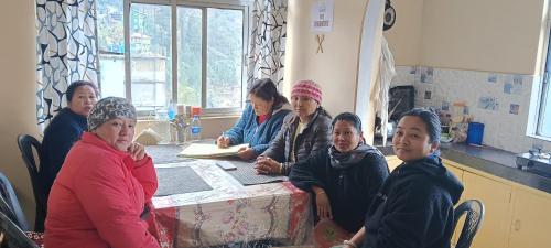 a group of women sitting at a table in a room at Ajay Homestay in Simāna Basti