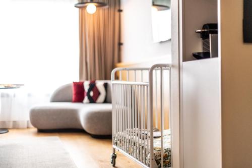 a living room with a couch and a crib at Le Louise Hotel Brussels - MGallery Collection in Brussels