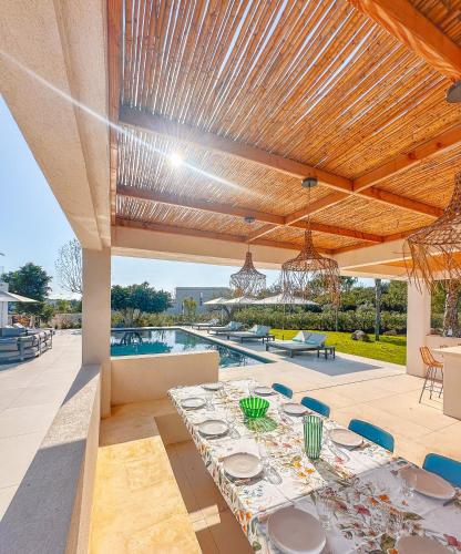 - un coin repas extérieur avec une table et une piscine dans l'établissement Villa Alimea San Ciprianu, à Cirendinu