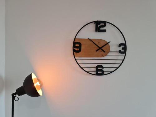 a clock hanging on a wall next to a lamp at Le ScottmanHouse - Appartement privé - Centre ville - Gare - Wi-Fi in Arras