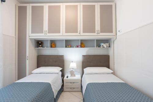 two beds in a bedroom with white cabinets at La Casa Vacanza Dei Sogni in Paestum