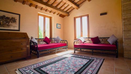 a living room with two red couches and a rug at Cantina D'Erasmo - Camere e Degustazioni in Offida