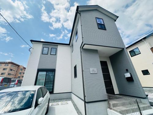 a white house with a car parked in front of it at 福の荘 空港1号棟 in Fukuoka