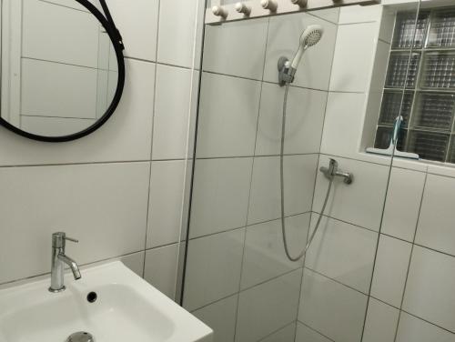 un bagno con doccia, lavandino e specchio di Comme chez vous a Saint-Joseph