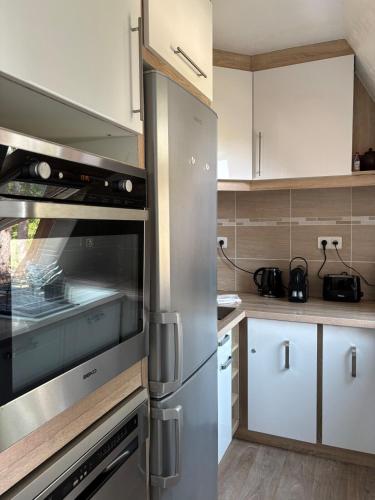 La cuisine est équipée de placards blancs et d'un four en acier inoxydable. dans l'établissement Appartement lumineux à 5 min de la plage, à Cabourg