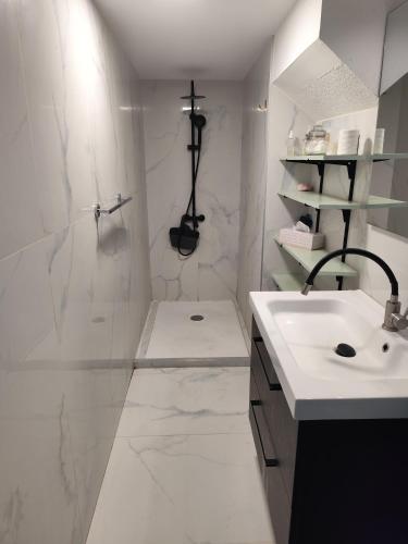 une salle de bain blanche avec un lavabo et une douche dans l'établissement RDC a 2 pas du port, à Port-Vendres