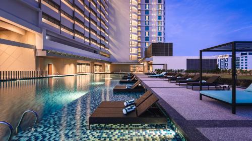 a hotel swimming pool with lounge chairs and a building at Holiday Inn & Suites Penang Prai by IHG in Bukit Mertajam