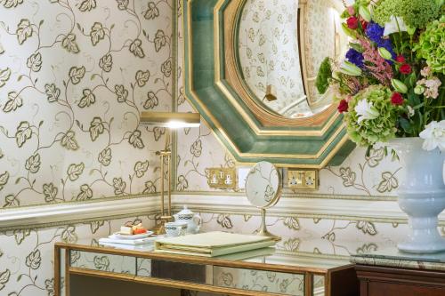 a dressing table with a vase of flowers and a mirror at Milestone Hotel Kensington in London