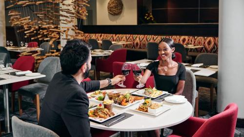 a man and a woman sitting at a table eating dinner at Crowne Plaza - Dar Es Salaam by IHG in Dar es Salaam
