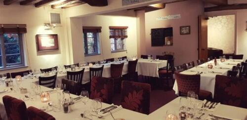 a dining room with tables and chairs with white tablecloths at OYO Blenheim House in Etwall