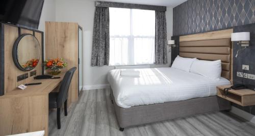 a bedroom with a bed and a desk and a mirror at Best Western Chiswick Palace & Suites London in London