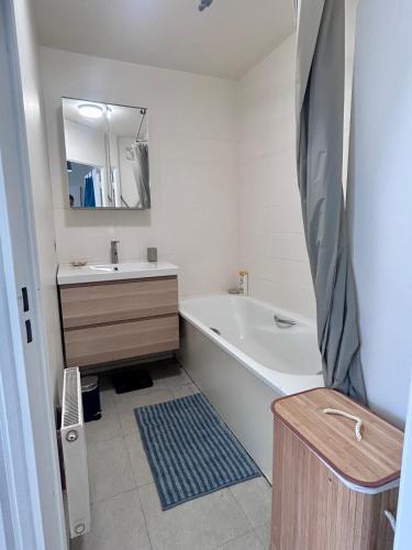 une salle de bain avec une baignoire, un lavabo et un miroir dans l'établissement Charmant 60m2 pour de 4 à 6 voyageurs, à Clichy