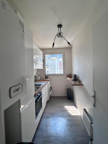 une cuisine avec un couloir doté d'un évier et d'une cuisinière dans l'établissement Charmant 60m2 pour de 4 à 6 voyageurs, à Clichy