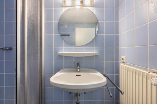 a blue tiled bathroom with a sink and a mirror at Gasthaus Hirschen Holl in Elbenschwand