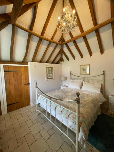 a bedroom with a bed and a ceiling with a chandelier at Acorns in Plaitford