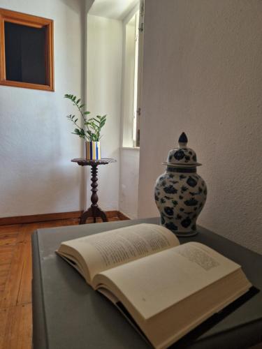 an open book sitting on a table with a vase at Casa do Botelho in Évora