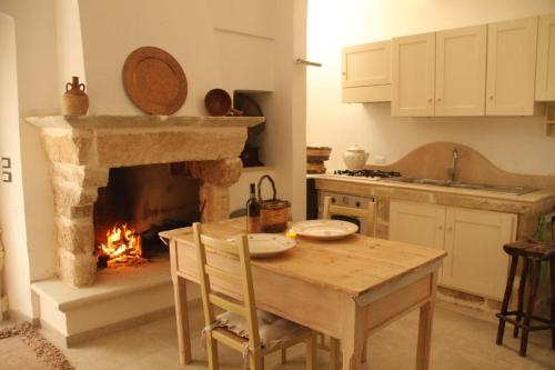 a kitchen with a wooden table and a fireplace at B&B Sara in Tuglie