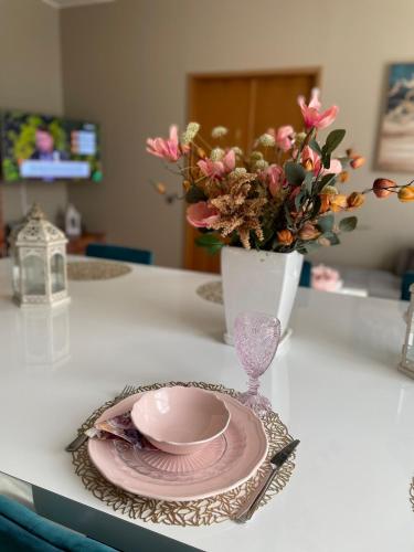 a vase with a pink plate and a vase with flowers at Kunderi apartment with sauna in Rakvere