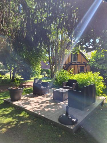 a group of chairs sitting on a patio under a tree at La petite maison in Le Bosc-Roger-en-Roumois
