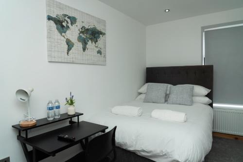 4 Bed Home, with 3 Bathrooms and Free Parking Home for Contractors & Workers- HOLIDAY PROMO FOR CHRISTMAS AND NEW YEAR في مانشستر: غرفة نوم بها سرير ومكتب وخريطة العالم على الحائط