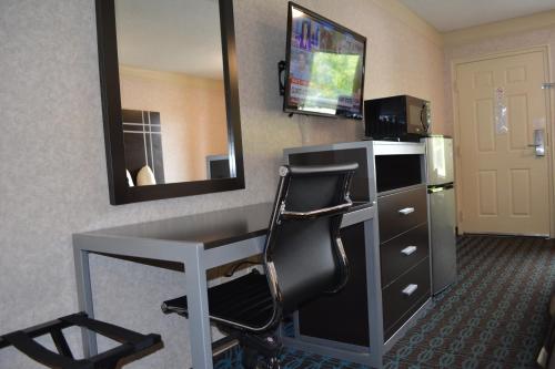 a hotel room with a desk and a mirror at Deluxe Inn - Fayetteville I-95 in Fayetteville