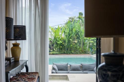 a living room with a view of a pool through a window at Luxurious Arakana Villa with Pool in Jimbaran