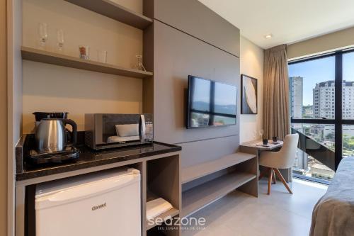 a room with a kitchen with a microwave and a desk at MHFA - Studios em Prédio Luxuoso com Vista Mar in Itapema