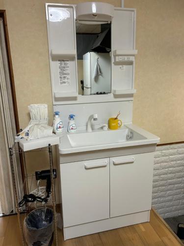 a kitchen with a white sink and a mirror at Kominkayado Gon in Tamano