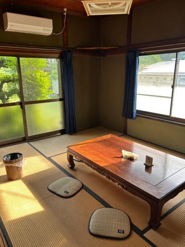 a room with a table in a room with windows at Kominkayado Gon in Tamano