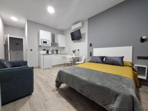 a bedroom with a bed and a couch and a kitchen at Medea Suites Apartamentos in Merida