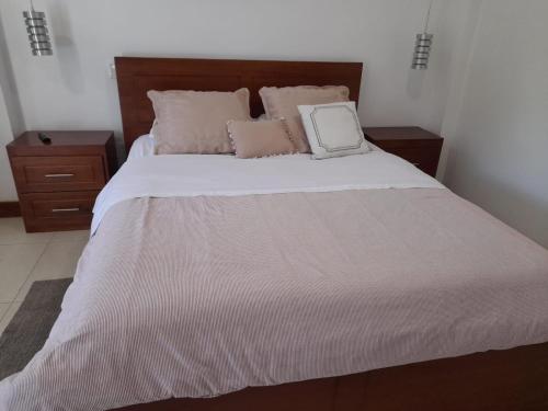 a bedroom with a large white bed with two pillows at Bamboo Village Place in Tumbaco