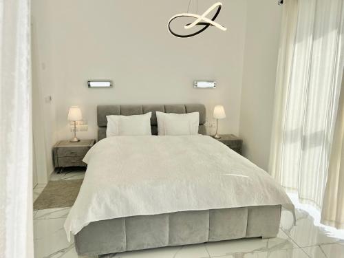 a white bedroom with a large bed and two lamps at Prince Palace Hadera Beach Resort in H̱adera