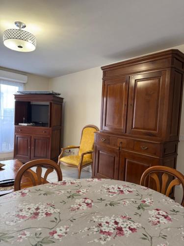 a dining room with a table and a wooden cabinet at Appartement Cosy in Fresnes