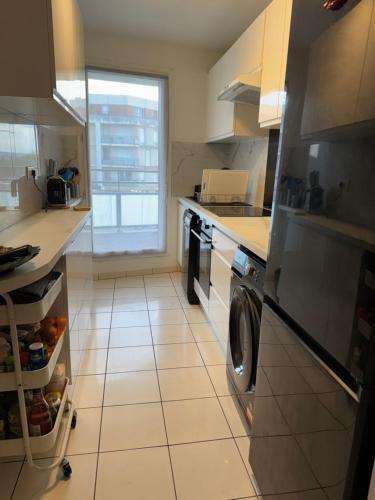 a kitchen with a refrigerator and a washer and dryer at Appartement Cosy in Fresnes