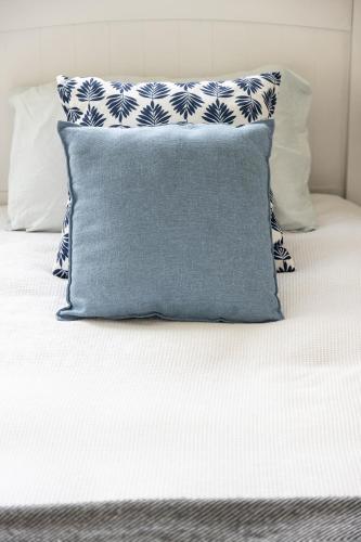 a bed with a blue and white pillow on it at Coastal Escape Watch Horses Pass Walk to Beach in Redcliffe