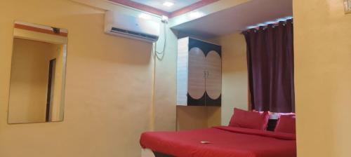 a bedroom with a red bed and a window at Hotel Krishna Palace in Dehu Road