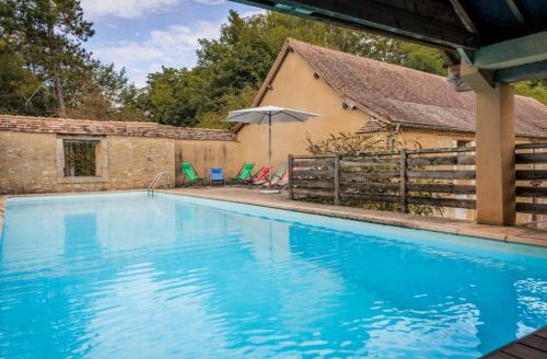 a blue swimming pool with chairs and an umbrella at L'Aile Est in Mayac