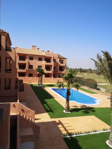 an apartment complex with a swimming pool and palm trees at Casa Matthis in Los Alcázares